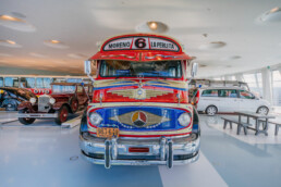 Mercedes-Benz Museum, Raum Collection 1: Galerie der Reisen. Omnibus Mercedes-Benz LO 1112 aus dem Jahr 1969. In Buenos Aires, Argentinien, sind die reich verzierten „Colectivo“-Busse über Jahrzehnte wichtige Bestandteile des Personennahverkehrs. Frontansicht.