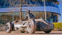 Mercedes-Benz Museum, Bronzeskulptur „Juan Manuel Fangio“ vor dem Museum zu Ehren des argentinischen Rennfahrers, 1954 und 1955 Formel-1-Weltmeister mit dem Silberpfeil Mercedes-Benz W 196 R.