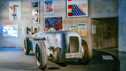 Mercedes-Benz Museum, Raum Mythos 7: Silberpfeile – Rennen und Rekorde. Im Vordergrund: Mercedes-Benz SSKL Avus-Rennwagen mit Stromlinienkarosserie, 1932. Originalgetreue Rekonstruktion aus dem Jahr 2019. Im Hintergrund: Neuerwerbungen der Mercedes-Benz Art Collection. Teil der Sonderausstellung „Moving in Stereo“, Highlights der Mercedes-Benz Art Collection, 27. Oktober 2022 bis 17. September 2023. Die Werke im Einzelnen von links, oben: Marius Glauer: Untitled II, 2015; Zanele Muholi: Zibandlela VI, III and II, The Sails, Durban, 2020; Farah Al Quasimi: Curtain Shop, 2019; Dawn Williams Boyd: The Trump Era: Trump’s America, 2020. Von links, unten: Cody Choi: When You Say No, You Know Something. When You Know Something Communication is Impossible [Wenn du nein sagst, weißt du etwas. Wenn du etwas weißt, ist Kommunikation unmöglich], 2010–2011; Zanele Muholi: Sine II, Sheraton Hotel, Brooklyn, 2019; Zanele Muholi: Gamalakhe I, 2018; Richard Mosse: Flooded Municipality, Amazonas, 2021; Natalie Czech: A Window View by Robert Creeley (Skyline), 2021, © VG Bild-Kunst Bonn, 2023. Hinweis: Die Verwendung des Fotos ist im Rahmen einer redaktionellen Berichterstattung über die oben genannte Ausstellung „Moving in Stereo“ gestattet.