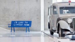 Innenansicht der Ausstellung „Now on View“ im Mercedes-Benz Museum mit einer blauen Bank von Künstler Finnegan Shannon.