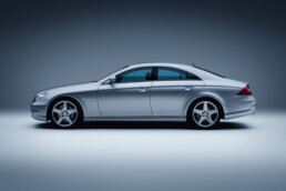 Mercedes-Benz CLS 55 AMG, Baujahr 2005 (Baureihe 219, Produktionszeit 2004 bis 2010). Studioaufnahme von links aus dem Jahr 2025.
