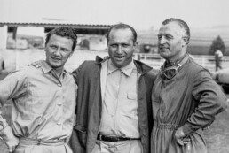 Hans Herrmann, Mercedes-Benz Werksrennfahrer in den Jahren 1954 und 1955. Foto vom Großen Preis von Frankreich in Reims, 4. Juli 1954. Das Mercedes-Benz Team von links: Hans Herrmann, Juan Manuel Fangio und Karl Kling. Fangio und Kling erzielen für die Marke einen Doppelsieg. Herrmann fährt die schnellste Runde. (Fotosignatur der Mercedes-Benz Classic Archive: R7058)