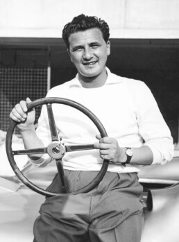 Hans Herrmann, Mercedes-Benz Werksrennfahrer 1954 und 1955. Foto von ihm mit dem Lenkrad des Mercedes-Benz W 196 anlässlich der Trainingsfahrten in Monza, August 1955. (Fotosignatur der Archive von Mercedes-Benz Classic: 55256-1)