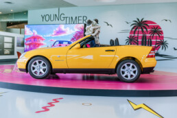 Mercedes-Benz SLK 230 Kompressor der Baureihe R 170 in der Lackierung yellowstone (Mercedes-Benz Farbcode 685) aus dem Jahr 1996. Aufnahme von links mit geöffnetem Verdeck in der Sonderausstellung „Youngtimer“ des Mercedes-Benz Museums, 2025. Foto: Thomas Niedermüller. (Fotosignatur der Archive von Mercedes-Benz Classic: D854691)