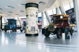 Mercedes-Benz Museum, Sonderausstellung „130 Jahre Nutzfahrzeuge“. Von rechts nach links: Benz 1C (1922), Mercedes-Benz 170 V Servicefahrzeug (1952) und Mercedes-Benz L 911 Kurzhauber-Lkw (1966). In der Mitte die Nachbildung einer historischen Litfaßsäule mit Informationen zur frühen Nutzfahrzeuggeschichte von Mercedes-Benz. Foto: Florian Schmucker