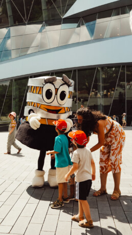 Mercedes-Benz Museum, Familientag am 13. Juli 2025. Carlotta, das Maskottchen des Mercedes-Benz Museums, mit Besuchern. Foto: JF Films. (Fotosignatur der Archive von Mercedes-Benz Classic: D861141)